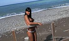 سخيفة في سن المراهقة امرأة سمراء مع الثدي وهمية ضخمة تطرح مباشرة على الشاطئ .