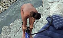 Tangában pompázó csaj mutatja meg a seggét egy nudista strandon